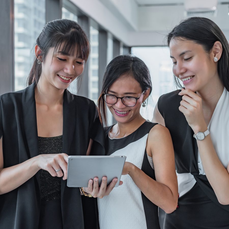 asian Business three woman look tablet  in modern office.